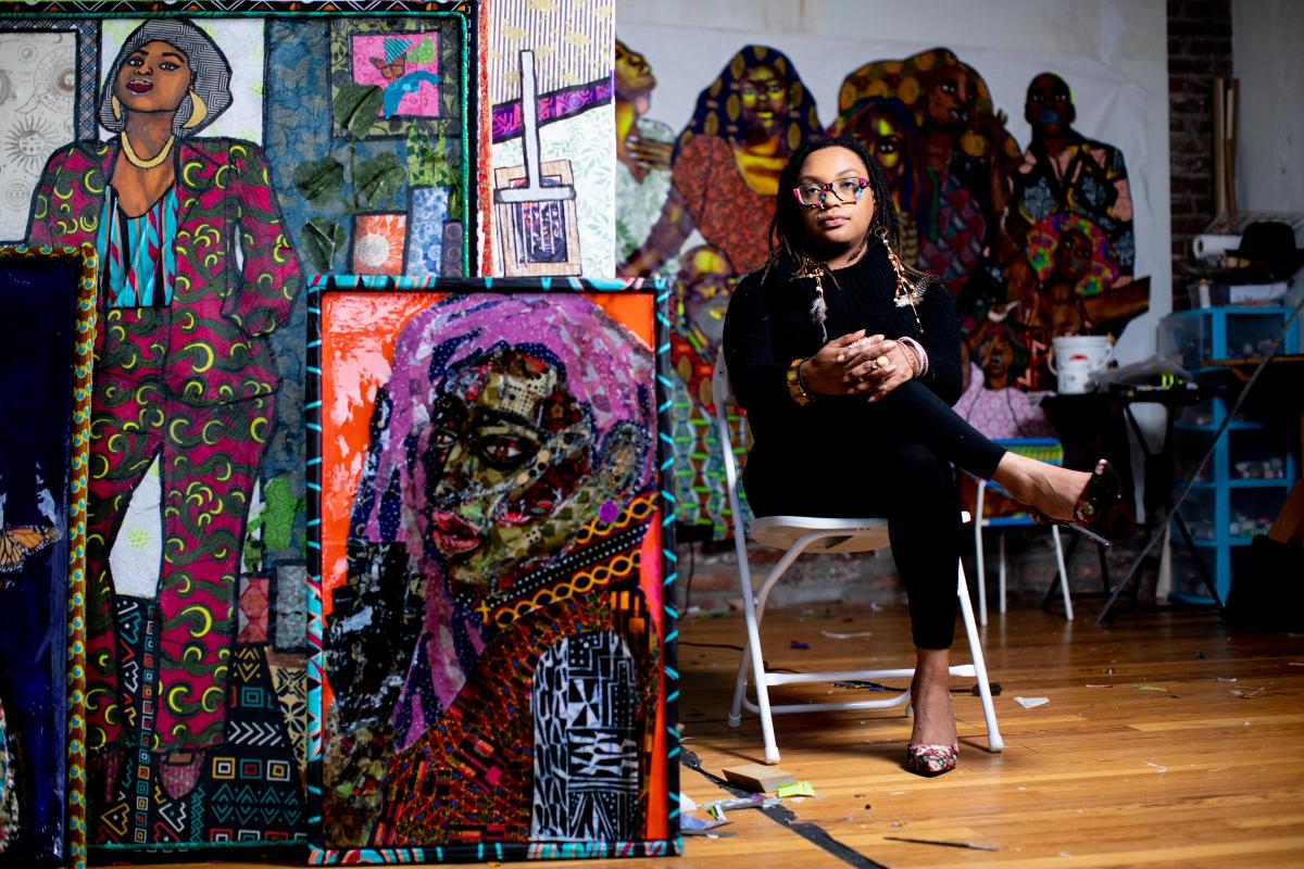 Zsudayka Nzinga sitting in her studio surrounded by her artwork