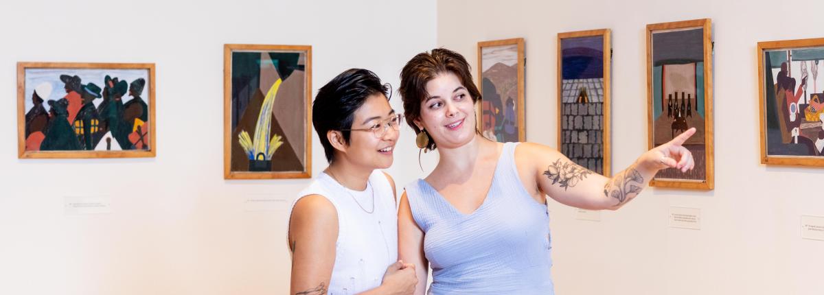 Photograph of two women in a gallery with Jacob Lawrence's Migration Series