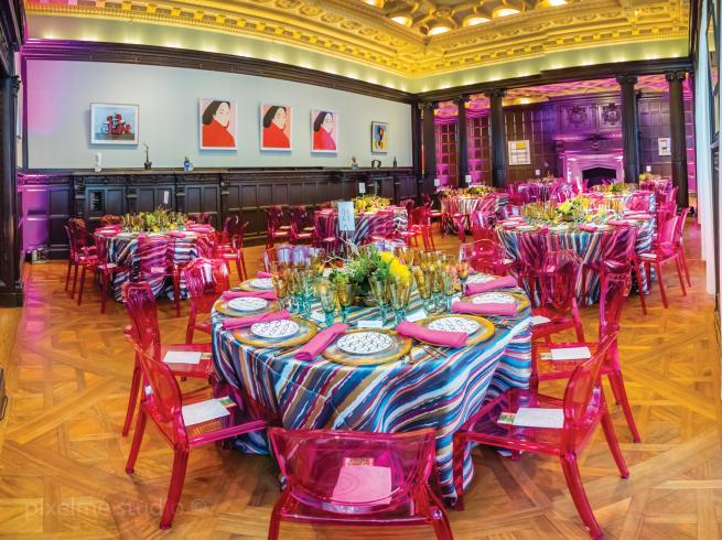 Photograph of room with very elaborate set up of table and chairs for a fancy event.