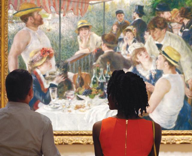 Two people sitting on a bench looking at Renoir's Luncheon of the Boating Party