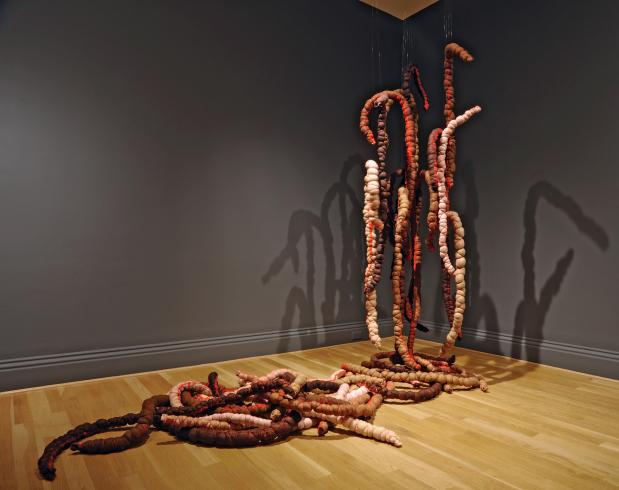 Abstract sculpture of pink and red strands made with fiber hanging from the ceiling and on the floor