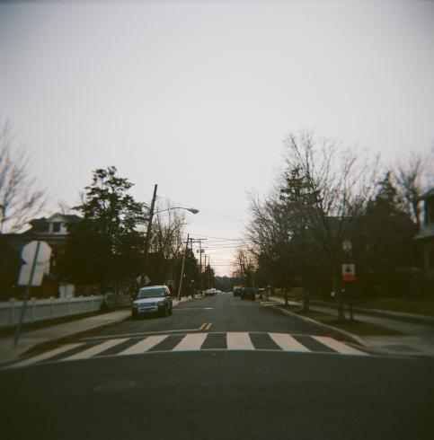 Image of an open street with one car parked on the left