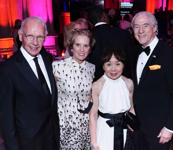 Photograph of four people in black tie standing together smiling at the camera