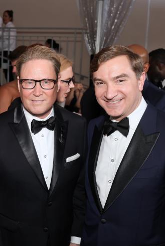 Photograph of two people in tuxes smiling at the camera