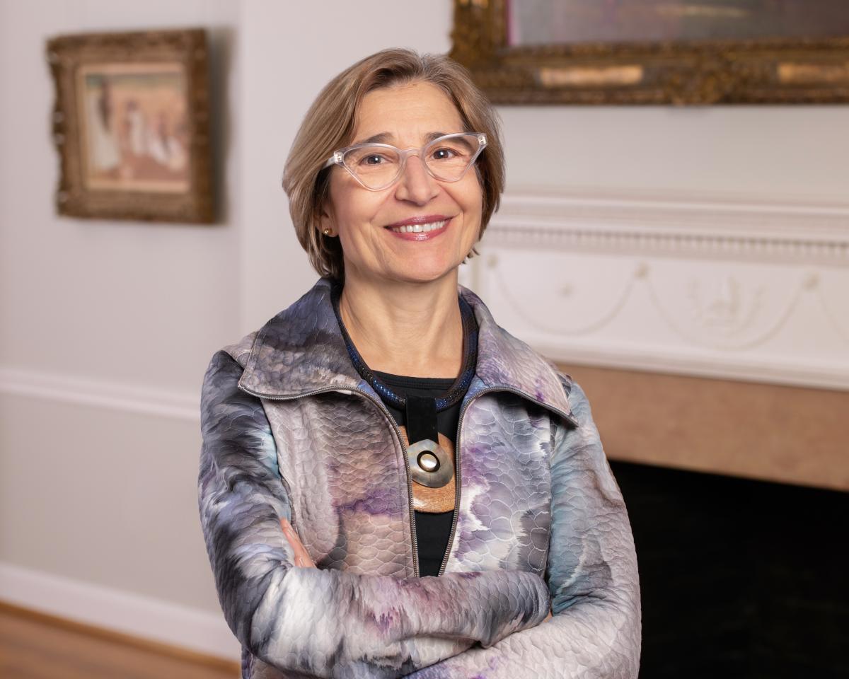 Vesela Stretenovic. Woman smiling wearing glasses and multi-colored jacket with her arms crossed.